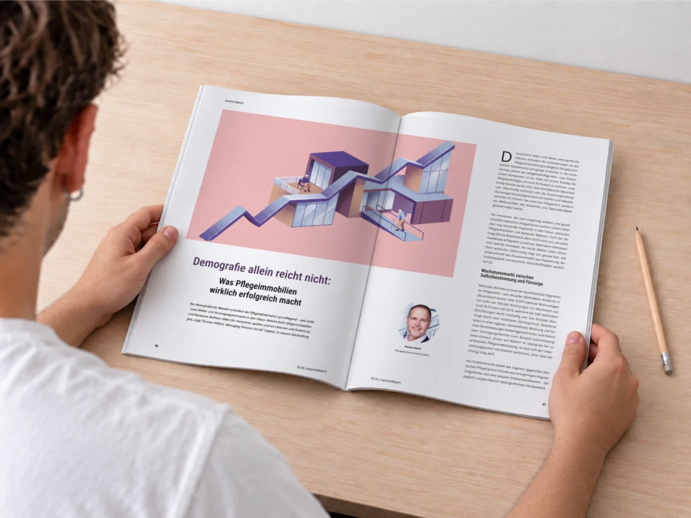 Blick über die Schulter auf eine aufgeschlagene Magazin-Doppelseite mit Illustration, Überschrift und Fließtext, daneben ein Bleistift